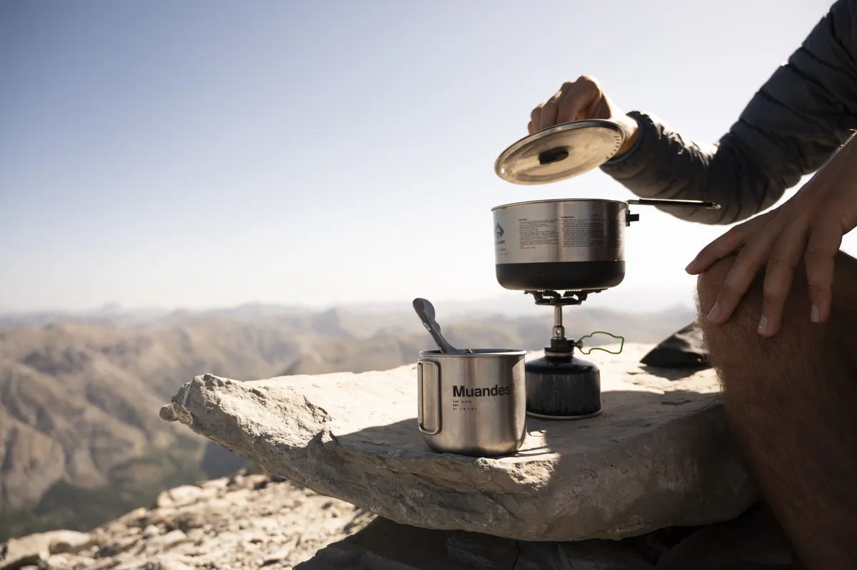 Un réchaud et une tasse Muandes posés sur un rocher