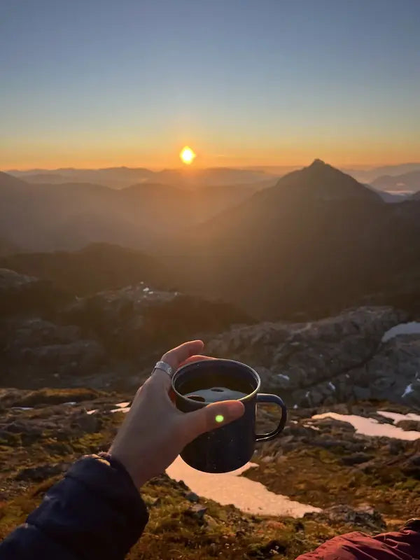Une tasse tenue face au soleil couchant