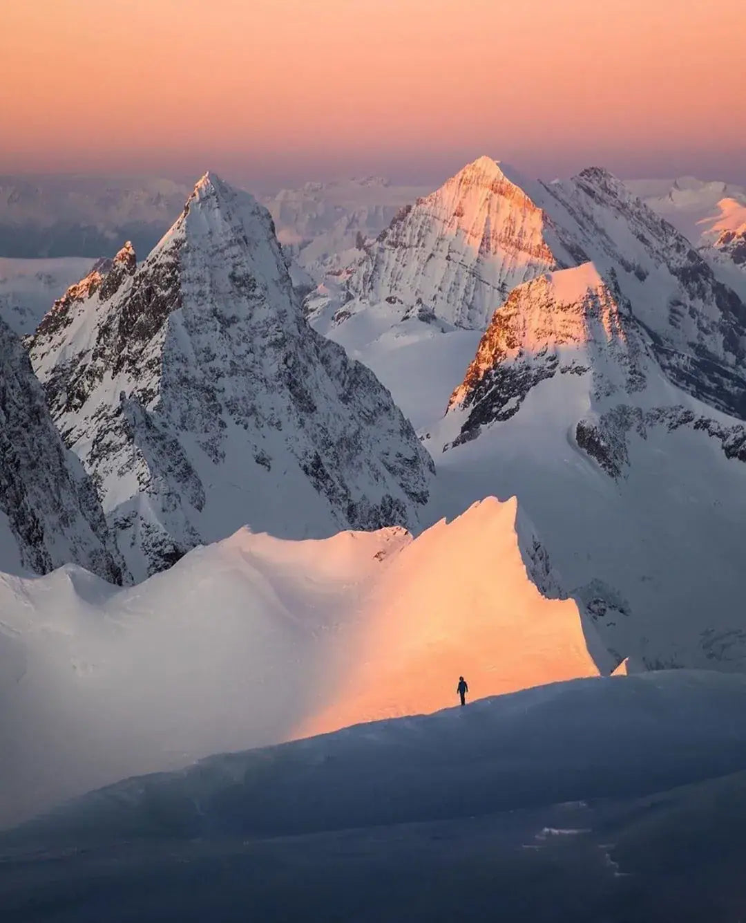 Une silhouette sur une arête enneigée au coucher du soleil
